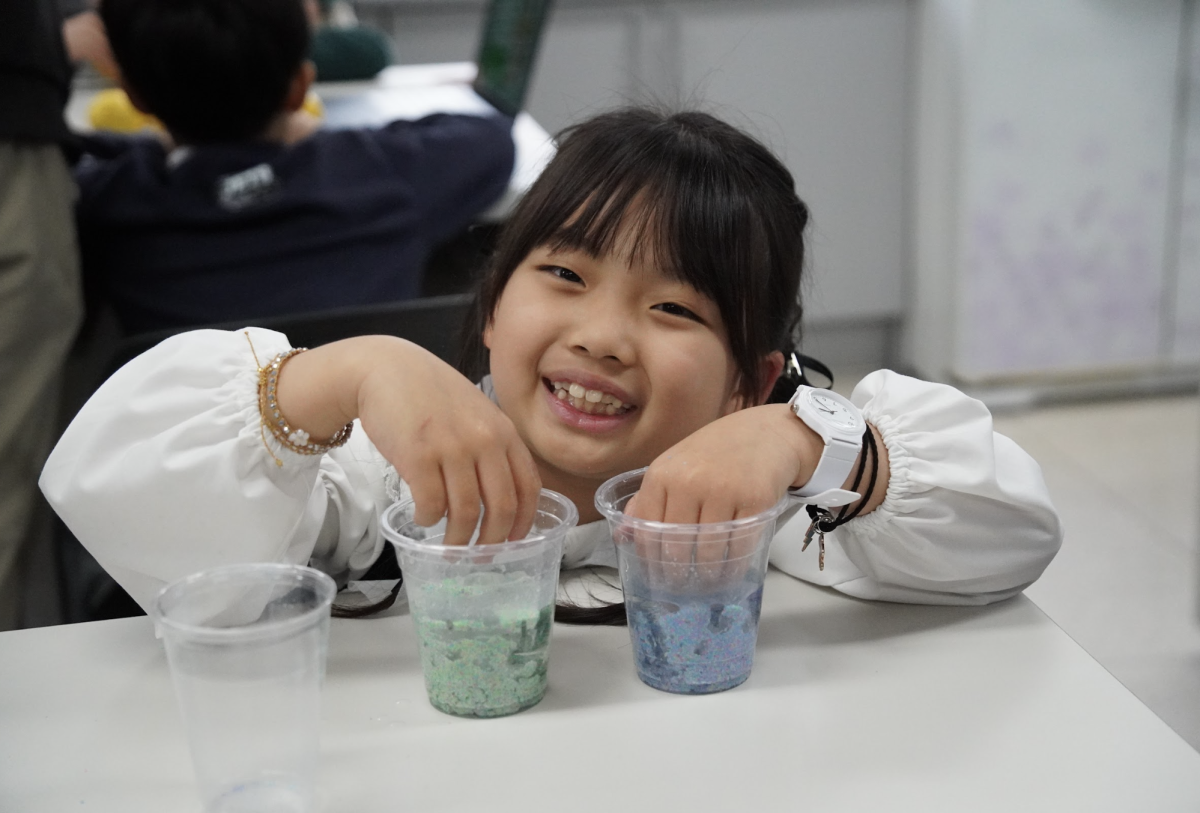 Second grader Ayla Cho watches as magic sand defies the water. She marvels at how the sand stays dry and separate from the liquid during her exploration of its mysterious properties.